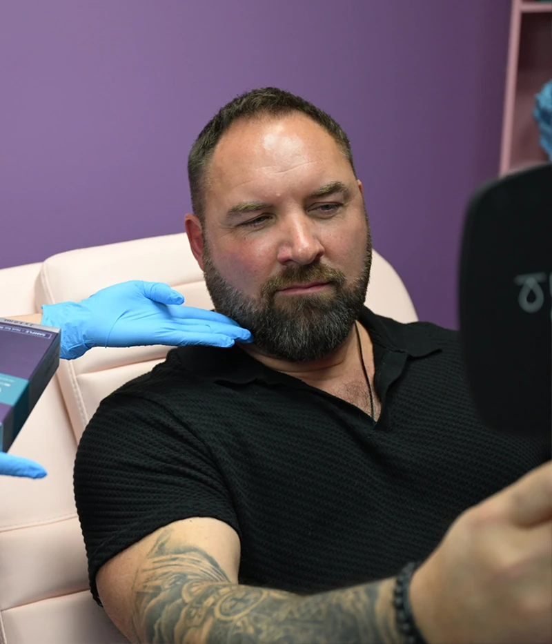 male dermfx client looking in mirror at injectable filler consult