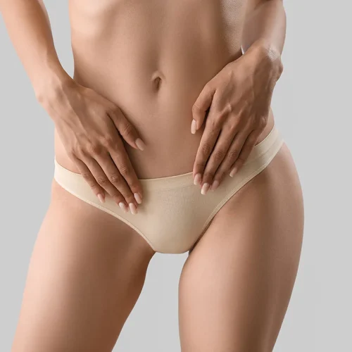 Slim young woman in underwear on light background